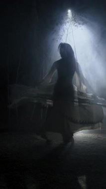 Gece ay ışığında dumanların altında dans eden dansçı silueti. Gizemcilik ve koreografi kavramı. Dikey video