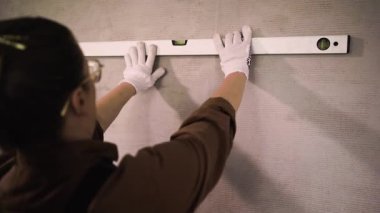 Tulumlu kadın, duvarları ruh seviyesiyle ölçüp evi yeniletiyor. Boşluğu kopyala