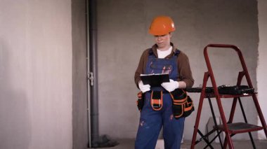 Müteahhit ve inşaat mühendisliği konsepti. Ustabaşı bina içerisindeki pano ile onarım ve teftiş yapıyor. Boşluğu kopyala