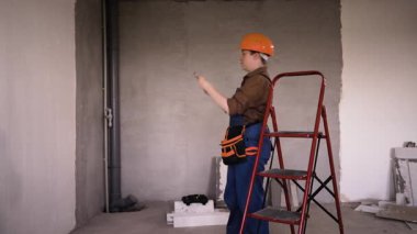 Turuncu kasklı kadın tamirci ya da inşaatçı içeride fotoğraf çekiyor. Boşluğu kopyala