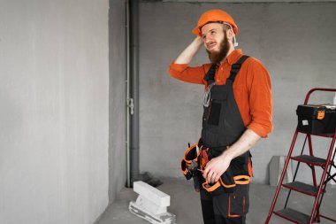 Sakallı bir tamirci ya da koruyucu kasklı ve tulumlu bir tamirci. Kafasını bina ekipmanlarıyla kaşıyarak kafasını karıştıran kafa karışıklığıyla ilgili şüpheleri var. Yapı ve onarım kavramı