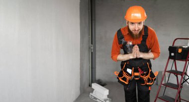 Sakallı tamirci ya da koruyucu miğferli ve tulumlu müteahhit dua ederken hayal kırıklığına uğramak için yalvarıyor. Yapı ve onarım kavramı