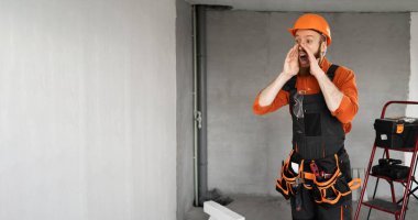 Sakallı bir tamirci ya da miğferli ve tulumlu bir tamirci el ele tutuşup bina malzemeleriyle odadaki reklamlara dikkat çekiyordu. Yapı ve onarım kavramı