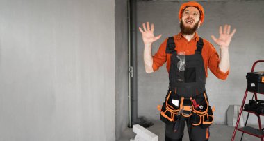 Sakallı miğferli ve tulumlu üzgün sinirli görünümlü kamera tamirat ve yenileme yapıyor. Boşluğu kopyala