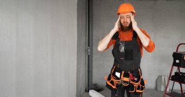 Baş ağrısı. Stresli erkek müteahhit ya da inşaat mühendisi baş ağrısı ve migrenden muzdarip, kendini kötü hissederken ev onarımı yapıyor. Boşluğu kopyala