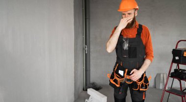 Çok kötü kokuyor. Başlık takan, burnu sıkan, tiksinti ifadesi olan genç müteahhit tadilattan sonra yeni bir evde duruyor. Pankart. Boşluğu kopyala