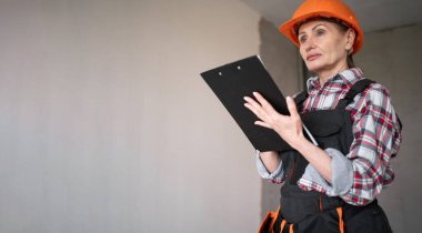 Kadın tamirci ya da işçi tulumlu, panoya notlar yazıyor. Evin tadilatı ve tadilatı. Pankart. Boşluğu kopyala