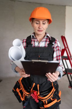 Evin tadilatı sırasında elinde dosya ve planlarla inşaat işçisi bir kadın. ev yenileme konsepti