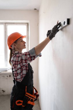 İnşaatçı bina inşaatı ya da tadilat sırasında ruh seviyesini kullanarak duvarı kontrol ediyor. Boşluğu kopyala