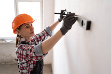 İnşaat sırasında ya da tadilat sırasında, ruhsal seviyeyi kalemle işaretleyerek duvarı kontrol eden bir inşaatçı. Boşluğu kopyala