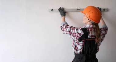 İnşaatçı bina inşaatı ya da tadilat sırasında ruh seviyesini kullanarak duvarı kontrol ediyor. Pankart. Uzayı kopyala Arka plan