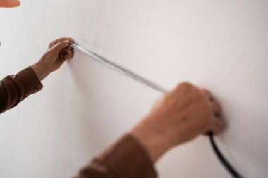 Duvarda mezura kullanarak üst düzey inşaat işçilerinin yakın çekimleri. Ev yenileme, yeniden inşa ve profesyonel tadilat kavramı