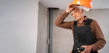 Kıdemli inşaatçının güvenlik kaskını çıkarması stres, depresyon ve işle ilgili sorunlar gösteriyor. Yaşlanma, ağır iş gücü ve duygusal çöküntü kavramı. Pankart