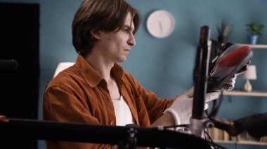 Günlük giysiler içinde yakışıklı bir adam evde bisikletinin koltuğunu tamir ediyor. Bisiklet montajı kavramı. Boşluğu kopyala