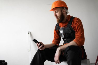 İnşaat alanında cep telefonu kullanan güvenlik kasketli mühendis. Boşluğu kopyala