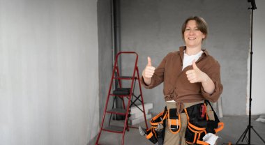 İyi iş çıkardın. Mutlu tamirci kadın baş parmağını kaldırıyor ve gülümsüyor. Ev onarımı ve tadilatı yapıyor. Pankart. Boşluğu kopyala