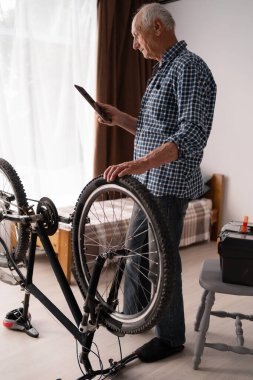 Yaşlı bir adam bir dairede bisiklet tamir eder. Tutkulu bir Kafkasyalı emekli bakım işiyle meşgul, pencerenin yanında duruyor ve elinde bir tablet tutuyor. Hobiler ve yetişkinlikte aktif bir yaşam tarzı.