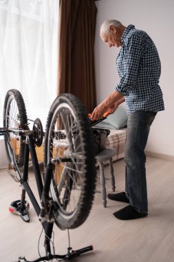 Kafkasyalı emekli adam evde bisiklet tamir eder. İlgili yaşlı adam alet çantasını açar. Boş zaman ve eğlence. Hobiler ve aktif yaşam tarzı