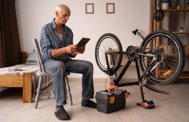 Yaşlı bir Kafkasyalı emekli evde bisikletini hevesle tamir ediyor. Adam bisikletin yanında otururken dikkatlice tablete bakıyor. İnternette video dersleri alma kavramı..