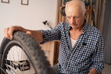 Emekli beyaz bir adam evde bisikletini tamir eder. Özenli yaşlı bir adam, bisikletini iyi durumda tutarak arka tekerleğe bakar. Boş zaman ve arama..