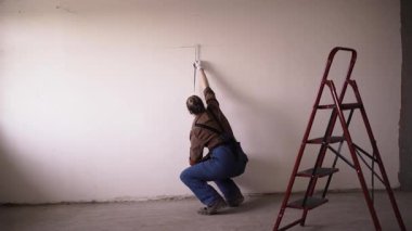 Odada bantla duvar boyunu ölçen becerikli bir kadın. Evin tadilatı ya da onarımı için tasarlanmış bir ölçü. Boşluğu kopyala