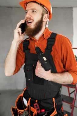 Foreman telefonla arıyor. İnşaatçı telefonla arıyor. Sakallı adam inşaat işçileri üniforması giyiyor. Kasklı tamirci. Boşluğu kopyala