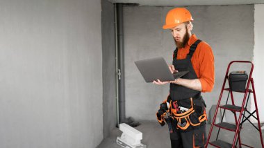 Küçük inşaat işlerini yürütmek için dizüstü bilgisayar kullanan işçi ya da tamirci. Hobi ve inşaat teknolojisi konsepti. Pankart. Boşluğu kopyala