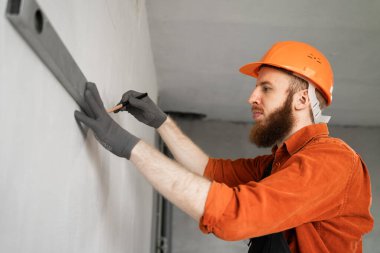 Duvar ölçmek için ruh seviyesini kullanan sakallı bir inşaatçının portresi. Boşluğu kopyala
