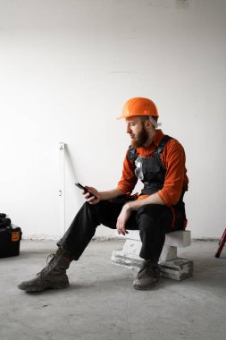Telefonu olan bir inşaatçı. İnşaat işçisi inşaat geliştirme için mesaj yazıyor, sohbet ediyor ve bilgi okuyor. Mobil uygulama. Boşluğu kopyala