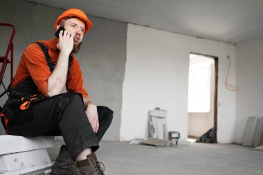 İnşaat işçisi ya da inşaatçı akıllı telefondan arıyor. meslek, teknoloji, inşaat ve inşa kavramı
