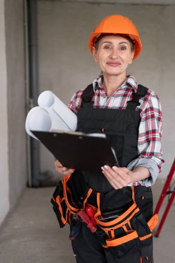 Evin tadilatı sırasında elinde dosya ve planlarla inşaat işçisi bir kadın. Yapıcı portresi