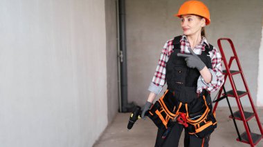 Duvardaki inşaat işçisinin parmak uçlarını gösteren reklam metinleri için mekanı gösteren kadın inşaat işçisinin portresi. Pankart. Boşluğu kopyala