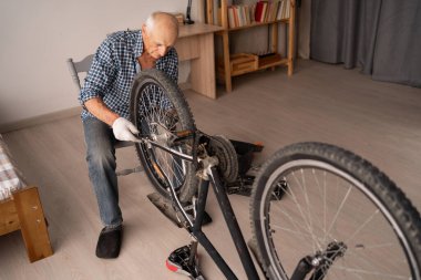 Aktif kıdemli adam evde bisiklet tamir ediyor. Boş vakitlerde bisiklet sürmek. Bisiklet bakım tekerlerini tamir etmek için ingiliz anahtarıyla çalışan emekli bir tamirci. Üst görünüm