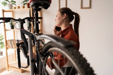 Genç bir kadın akıllı telefonda teknisyenle bozuk bisikleti tamir etmek hakkında konuşuyor. Tamirciyle akıllı telefon görüşmesi. Boşluğu kopyala