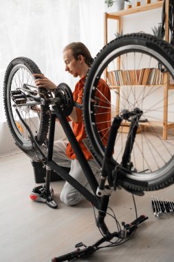 young man repairing and securing bicycle at home for cycling leisure. male hipster bike maintenance. copy space