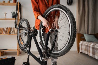 Young man fixing his bicycle at home using a spanner fix wheels, close-up. Bicycle repair and maintenance concept