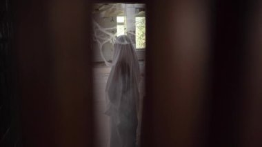 Beyaz çarşaflı cadılar bayramı hayaleti yıkılmış bir binada örümcek ağlarının arasında duruyor. Cadılar Bayramı korku konsepti. Boşluğu kopyala