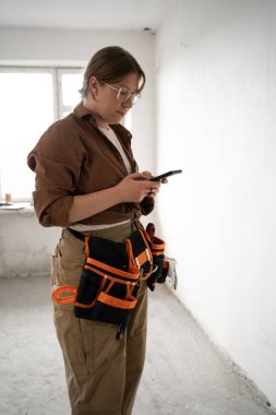 İnşaat işçisi ya da tamirci odada akıllı telefon kullanıyor. meslek, inşaat ve onarım konsepti. Boşluğu kopyala