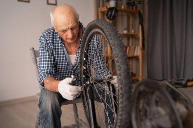 Diy konsepti. Emekli bisikletçi, tamirat sırasında bisikleti kontrol ediyor. Boşluğu kopyala
