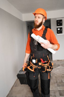 Sakallı tamirci, elinde taslak, alet çantası ve kemer ile çalışan aletler tutan kasklı işçiler. Onarım, inşaat ve inşaat kavramı