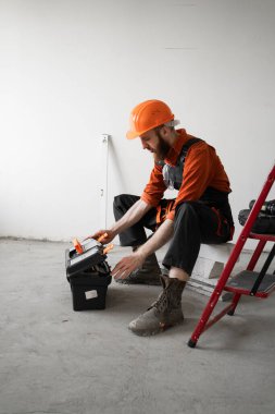 Tamirci evde ya da ofiste tamir etmeden önce merdiven başında oturmuş alet çantası açıyor. Boşluğu kopyala