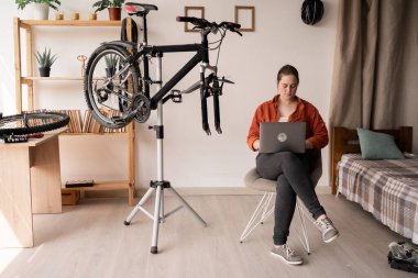 Diz üstü bilgisayarlı bir bisikletçi hasarlı bisikletinin tamir edilmesine yardım etmek için talimat verdi. Boşluğu kopyala