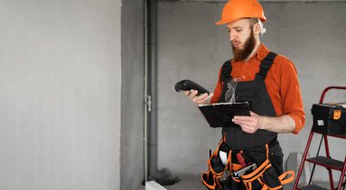 Tamir masrafları. İnşaat alanında sakallı bir inşaatçı ve hesap makinesi var. İnşaat tahmini... Uzayı kopyala Pankart