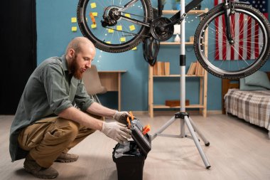 Beyaz sakallı adam evde bisiklet tamir eden aletlerle alet kutusunu açıyor. Motosiklet bakım kavramı