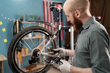 Bisiklet tamir etmeye çalışan bir adam atölyede kullanacağı ingiliz anahtarını seçiyor. Boşluğu kopyala