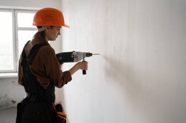 İnşaat alanında matkap delici kullanan bir kadın müteahhit. Boşluğu kopyala