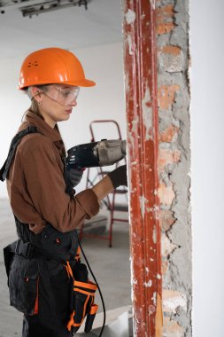Ev Yenileme sırasında Ahşap Kapı 'yı kaldırmak için Döner Çekiç kullanan Güvenlik Gözlüklü Kadın İnşaatçı. Boşluğu kopyala