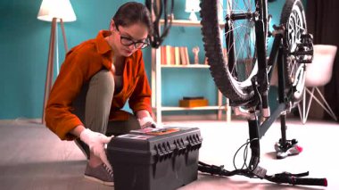 Bisikletle çalışan genç bir bisikletçi bisiklet kutusunu açmak için bisiklet ekipmanı kullanıyor. Boşluğu kopyala