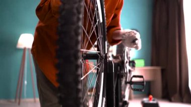 Evde tamirat sırasında el anahtarıyla bisiklet tekerleğini sıkan kadın bir tamirci. Yakın plan.