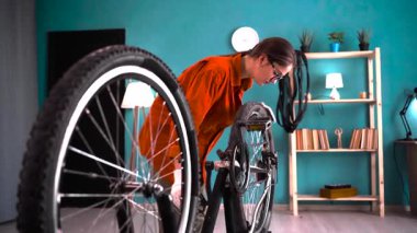 Aktif genç kadın pedallara motor bakım ayarları yapıyor ve evde tekerlekleri kontrol ediyor. Boşluğu kopyala